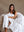 A woman sitting in a cozy chair with a white, fluffy blanket wrapped around her shoulders.