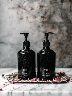 Two black bottles labeled 'Tatine Kashmir' on a decorative tray with a blurred background