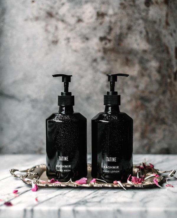 Two black bottles labeled 'Tatine Kashmir' on a decorative tray with a blurred background